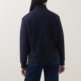 Model wearing Gant Shield Logo Half-Zip Sweatshirt in blue, rear view showing half-zip, funnel neck and ribbed cuffs, styled with dark jeans.