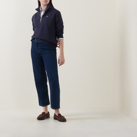 Model wearing Gant Shield Logo Half-Zip Sweatshirt in blue with dark wash cropped jeans and brown loafers.