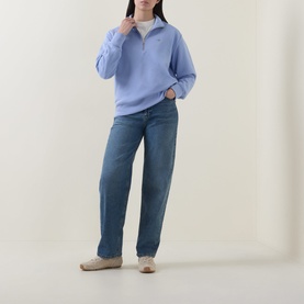 Model wearing Gant Shield Logo Half-Zip Sweatshirt in lavender with blue straight-leg jeans and beige loafers.