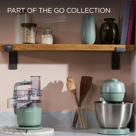 Kenwood Go Collection in green: hand mixer, food processor, and stand mixer displayed on marble countertop with wooden shelf above