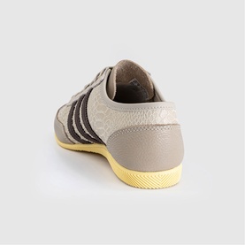 Adidas trainer in wonder beige and dark brown with three-stripe detail, textured upper and yellow gum sole, rear three-quarter view.
