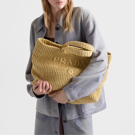 Model carrying Prada Accessories large neutral woven raffia tote bag, styled with a grey oversized jacket