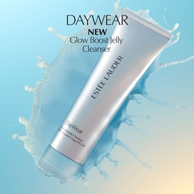 Est&eacute;e Lauder DayWear Glow Boost Gel Cleanser in white tube, shown with water splash on light blue background