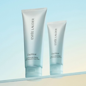 Estee Lauder DayWear Glow Boost Gel Cleanser in two sizes, soft blue tubes displayed upright against a light gradient background.