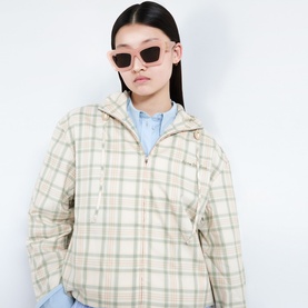 Model with Loewe Anagram Cat-Eye Sunglasses in pink, cat-eye frame with gold-tone hardware, styled with cream check hooded jacket