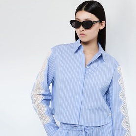 Model with Loewe Slim Logo Geometric Sunglasses in black, cat-eye shape with slim arms, styled with a blue striped shirt with lace sleeves
