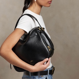 Model carrying Polo Ralph Lauren black leather satchel with gold-tone hardware, styled with white tee and blue jeans.