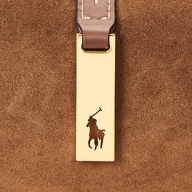 Polo Ralph Lauren shoulder bag in Cinnamon/Cuoio suede, close-up of gold-tone hardware clasp with engraved polo pony motif and brown leather strap.