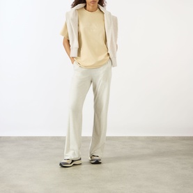 Model wearing Adanola Logo Graphic Oversized T-Shirt in Caramel Beige, styled with cream wide-leg trousers, cream blazer and grey trainers.