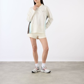 Model wearing Adanola Marshmellow White pullover top with colour-block panels, styled with matching shorts and white trainers.
