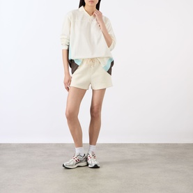 Model wearing Adanola Marshmellow White cropped sweatshirt with colour-block shorts and chunky trainers.