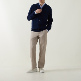 Model wearing Aspesi Blue Knitted Polo Shirt cardigan with button fastenings, styled with a printed shirt, beige trousers and white trainers.