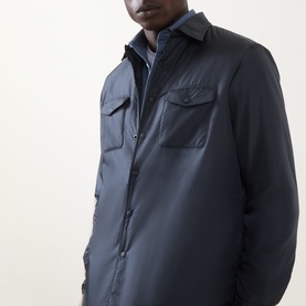 Model wearing Aspesi navy nylon casual jacket with chest pockets, styled over a chambray shirt.