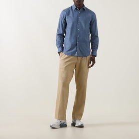 Model wearing Aspesi light blue cotton casual shirt with beige chinos and grey trainers