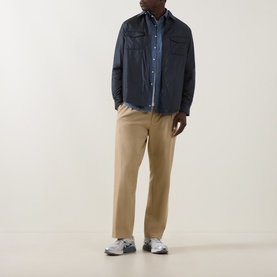 Model wearing Aspesi light blue cotton casual shirt, styled with navy overshirt, beige trousers and grey trainers.