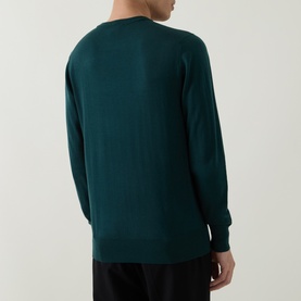 Model wearing Aspesi Solid Wool Sweater in green, rear view showing crew neck, long sleeves and ribbed trims, styled with black trousers.