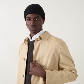 Model with Aspesi Rib-Knit Beanie Hat in black wool with turn-up hem, styled with a beige coat and dark knit layer.
