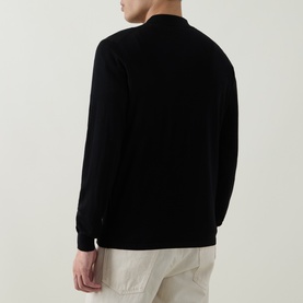 Model wearing Aspesi Solid Knitted Polo Shirt in black wool, rear view, with ribbed trims and long sleeves, styled with cream trousers.