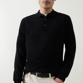 Model wearing Aspesi Solid Knitted Polo Shirt in black wool, long sleeves, polo collar with button placket, styled with cream trousers.