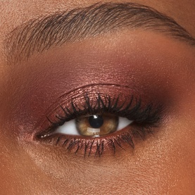Charlotte Tilbury Eyeshadow in Oyster Twilight worn on model's eye, showing a deep burgundy and rose gold smoky eye look