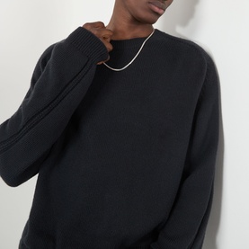 Model wearing Our Legacy True Knitted Sweater in Black Cloud Cotton, crew neck, ribbed trims, styled with a silver chain necklace.