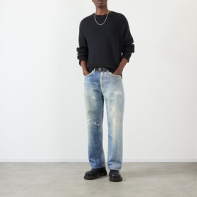 Model wearing Our Legacy True Knitted Sweater in Black Cloud Cotton with distressed light-wash jeans and black chunky loafers.
