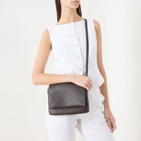 Model carrying Gianni Chiarini Three Flap Leather Crossbody Bag in brown, grained leather with silver-tone hardware, worn crossbody. Styled with