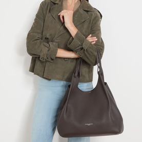 Model carrying Gianni Chiarini Dua Leather Tote Bag in brown grained leather with looped handles, styled with green suede jacket and jeans