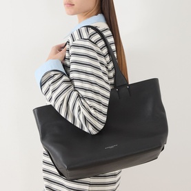 Model carrying Gianni Chiarini Barbara Tote Bag in Nero grained leather with silver-tone hardware and carry handles, styled with striped top