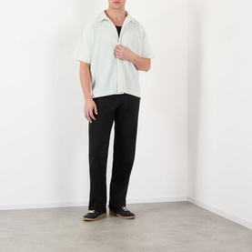 Model wearing Issey Miyake casual shirt in Duomo Green, short-sleeved with camp collar, styled with black straight-leg trousers and dark loafers