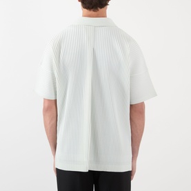 Model wearing Issey Miyake casual shirt in Duomo Green, shown from the back, with all-over pleated texture and short sleeves.