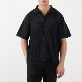 Model wearing Issey Miyake black pleated short-sleeve casual shirt with open collar and button front, styled with black trousers.