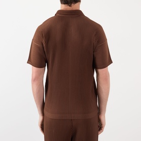 Model wearing Issey Miyake anchor brown ribbed pleated polo shirt, short sleeves, back view, styled with matching trousers