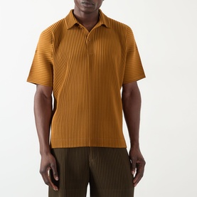 Model wearing Issey Miyake polo in Venice Boat Brown with ribbed pleated texture and open collar, styled with matching pleated trousers.