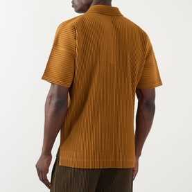 Model wearing Issey Miyake polo in Venice Boat Brown, rear view, with ribbed texture and short sleeves, styled with dark trousers.