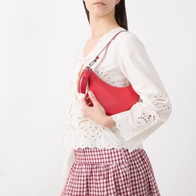 Model carrying Kate Spade Duo Mini Shoulder Bag in Heirloom Tomato red pebbled leather with silver-tone hardware, styled with white broderie blouse
