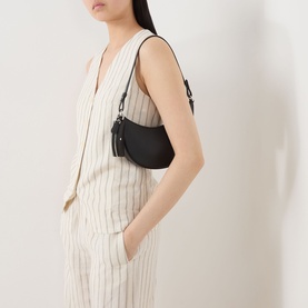 Model carrying Kate Spade Duo Mini Shoulder Bag in black pebbled leather with silver-tone hardware, styled with cream pinstripe co-ord set.