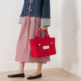 Model carrying Kate Spade Dash Strawberry Canvas Tote Bag in Ruby Red, silver-tone hardware, styled with gingham skirt and denim jacket.