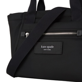 Kate Spade Dash Nylon Tote Bag in black, close-up showing front zip pocket, logo badge, and silver-tone hardware detail
