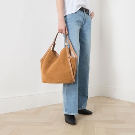 Model carrying Kate Spade Deco Tulip Suede Tote Bag in Garden Soil, tulip silhouette with gold-tone handles, styled with jeans and black ankle boots