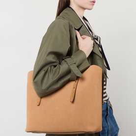Model carrying Kate Spade Do It All Wavy Tote Bag in Garden Soil suede, gold-tone hardware, scalloped trim, styled with olive jacket and jeans