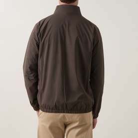 Model wearing Peter Millar Ryder 3-in-1 Jacket in Ash Brown, rear view, showing bomber-style silhouette with elasticated hem, styled with beige