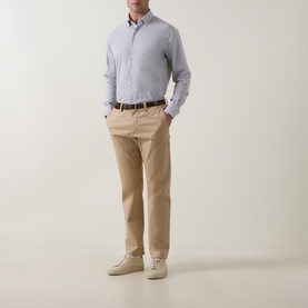 Model wearing Peter Millar black casual shirt with beige chinos, brown belt and cream trainers