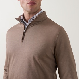 Model wearing Peter Millar Light Mocha half zip pullover, styled with a blue gingham shirt visible at collar