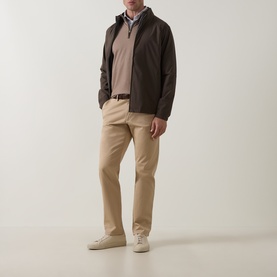 Model wearing Peter Millar Light Mocha Half Zip, styled with dark brown jacket, beige chinos and white trainers.
