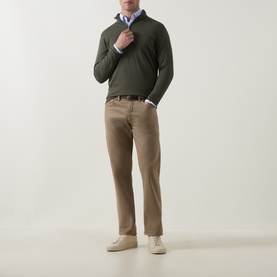 Model wearing Peter Millar Dark Olive Half Zip over a blue shirt, styled with tan trousers and cream trainers.