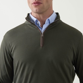 Model wearing Peter Millar Dark Olive half zip pullover with brown zip detail, styled with a light blue collared shirt underneath.