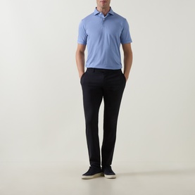Model wearing Peter Millar Empire Performance Polo Shirt in Windy Blue with spread collar, styled with navy trousers and dark trainers.