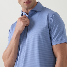 Model wearing Peter Millar Empire Performance Polo Shirt in Windy Blue, showing spread collar and two-button placket with tonal textured fabric detail