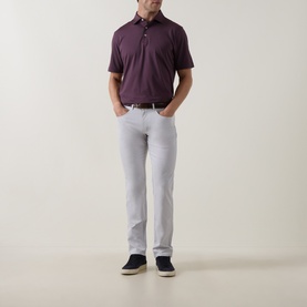 Model wearing Peter Millar polo in Bordeaux, styled with light grey trousers, white belt and navy suede loafers